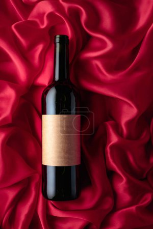 Téléchargez les photos : Bottle of red wine with an empty label on a satin background. Top view. - en image libre de droit