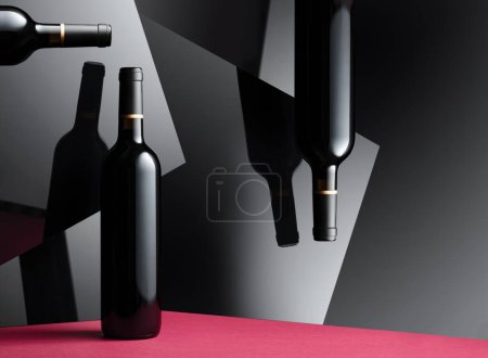 Téléchargez les photos : Bouteilles de vin rouge avec une réflexion sur les surfaces noires brillantes. Concept du thème du vin cher. - en image libre de droit
