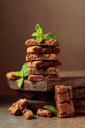Téléchargez les photos : Pieces of fresh brownie with mint on a rustic brown background. - en image libre de droit