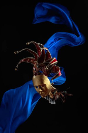 Foto de Máscaras de carnaval antiguas sobre un fondo negro con aleteo de tela azul. - Imagen libre de derechos