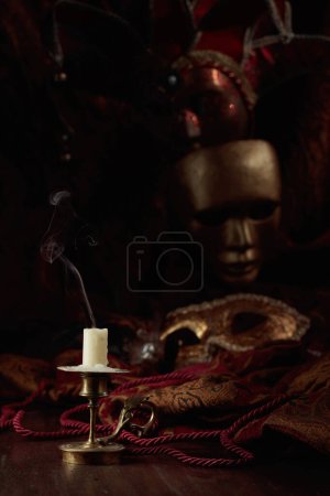 Photo for Still life with an extinguished candle in an old brass candlestick and carnival masks. - Royalty Free Image