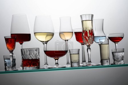 Téléchargez les photos : Various alcoholic drinks in a bar on a tilted glass shelf. - en image libre de droit