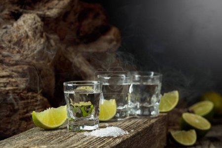 Téléchargez les photos : Tequila with salt and lime slices on an old wooden board. - en image libre de droit