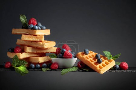 Photo for Waffles with  blueberries, raspberries,  and fresh mint a dark background. - Royalty Free Image