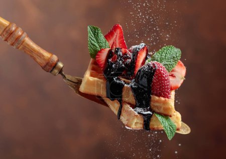 Téléchargez les photos : Gaufres belges aux fraises, menthe et sauce au chocolat, saupoudrées de sucre en poudre. - en image libre de droit