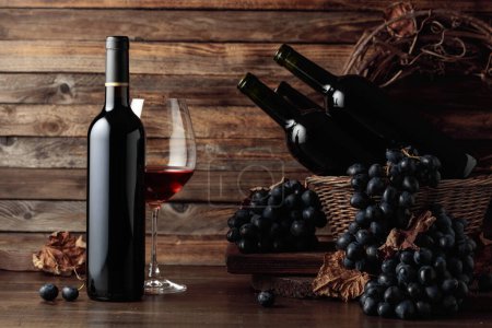 Foto de Red wine and blue grapes. Wine and grapes in a vintage setting on an old wooden table. - Imagen libre de derechos