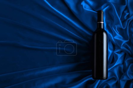 Téléchargez les photos : Bottle of red wine on a blue satin background. Top view. - en image libre de droit
