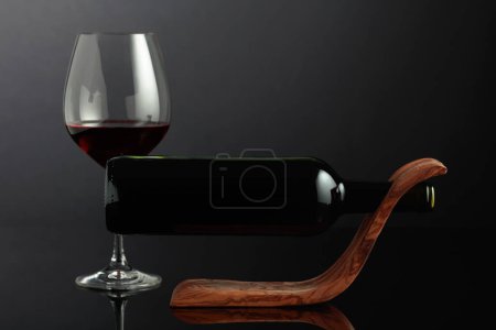 Téléchargez les photos : Bottle of red wine in a wooden bottle holder on a black reflective background. Copy space. - en image libre de droit