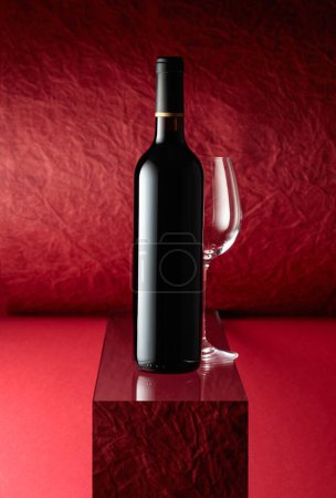 Téléchargez les photos : Bottle of red wine and an empty wine glass on a red background. - en image libre de droit