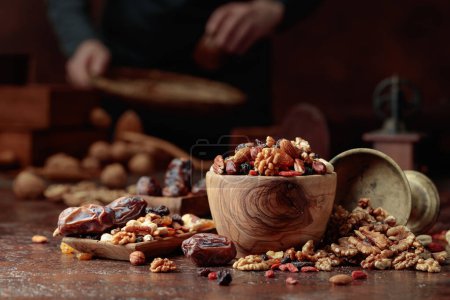 Foto de Varios frutos secos y frutos secos están en un tazón de madera en una mesa de cocina. Enfoque selectivo. - Imagen libre de derechos