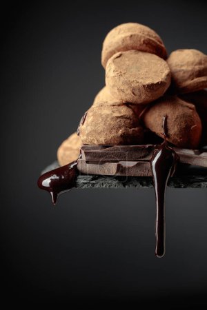Photo for Delicious chocolate truffles and falling drops of chocolate sauce on a black background. - Royalty Free Image