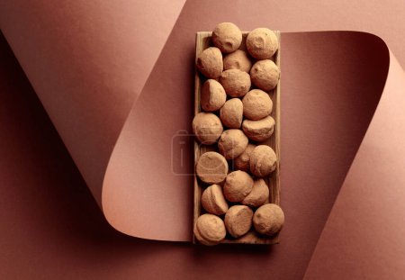 Foto de Deliciosas trufas de chocolate en un plato de madera sobre fondo marrón. Vista superior. Copiar espacio. - Imagen libre de derechos