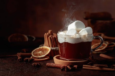Foto de Chocolate caliente con malvaviscos. Bebida de invierno con especias sobre un fondo marrón oscuro. - Imagen libre de derechos