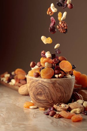 Photo for Flying dried fruits and nuts. The mix of nuts and raisins in a wooden bowl. - Royalty Free Image