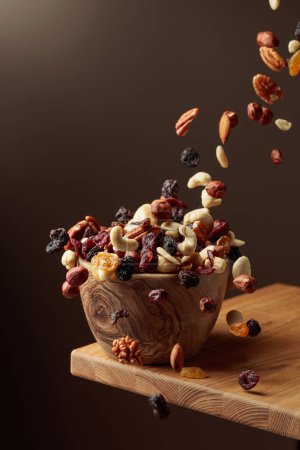 Foto de Frutos secos voladores y nueces. La mezcla de frutos secos y bayas secas están en un tazón de madera. - Imagen libre de derechos