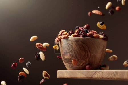 Photo for Flying dried fruits and nuts. The mix of nuts and dried berries are in a wooden bowl. - Royalty Free Image