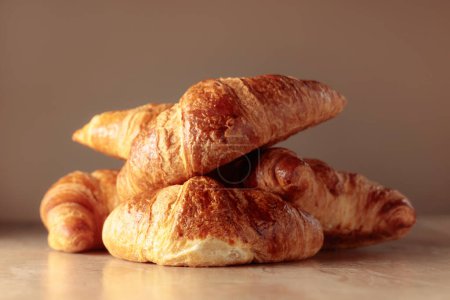 Foto de Freshly baked croissants on a beige ceramic table. Traditional French kitchen. - Imagen libre de derechos