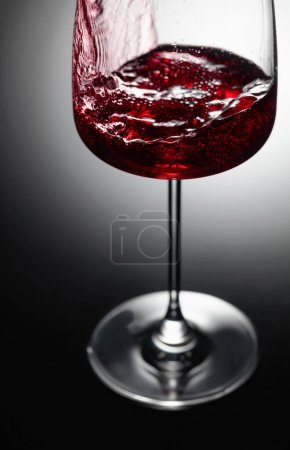 Photo for Closeup of red wine pouring on a black background. - Royalty Free Image
