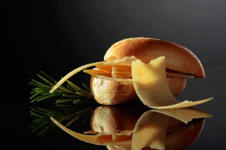 Téléchargez les photos : Sandwich with Parmesan cheese and rosemary on a black reflective background. - en image libre de droit