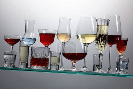 Photo for Various alcoholic drinks in a bar on a tilted glass shelf. - Royalty Free Image