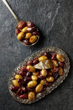 Foto de Spicy olives on a black stone table. Top view. - Imagen libre de derechos