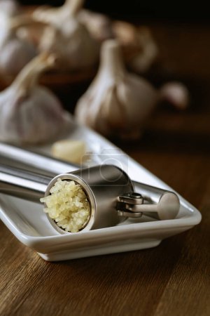 Foto de Garlic bulbs and garlic press on an old wooden table. - Imagen libre de derechos