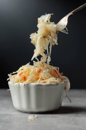 Foto de Bowl of sauerkraut with a carrot on a grey stone table. - Imagen libre de derechos