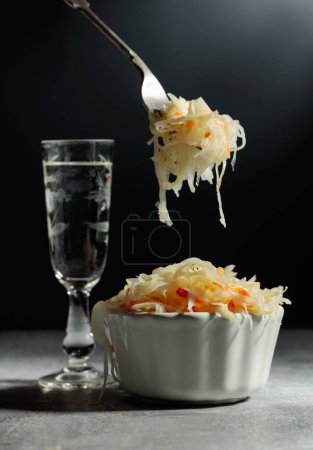 Téléchargez les photos : Bowl of sauerkraut and a glass of vodka on a grey stone table. - en image libre de droit
