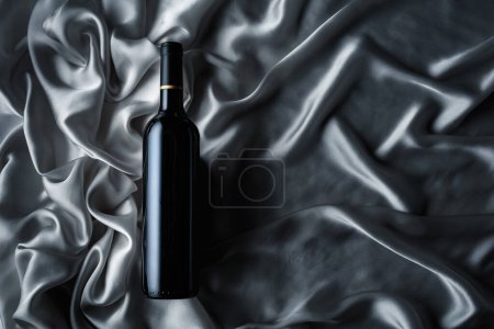 Téléchargez les photos : Bouteille de vin rouge sur fond de satin gris. Vue du dessus. - en image libre de droit