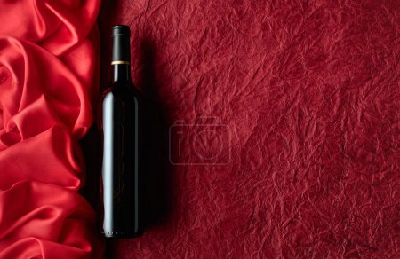 Téléchargez les photos : Bouteille de vin rouge sur fond rouge. Vue du dessus. - en image libre de droit