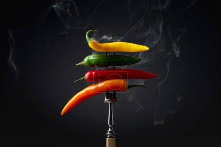Téléchargez les photos : Hot chili peppers with smoke on a black background. Concept of spicy food. - en image libre de droit