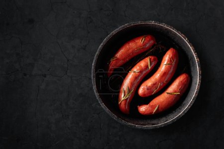 Téléchargez les photos : Saucisses bavaroises rôties au romarin sur une table en pierre noire. Espace de copie. - en image libre de droit