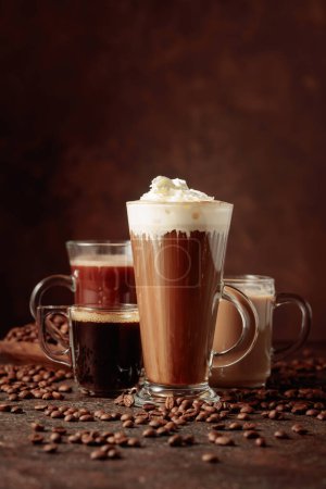 Téléchargez les photos : Diverses boissons au café et au chocolat avec des grains de café éparpillés sur un fond brun. Espace de copie. - en image libre de droit