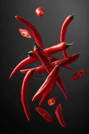 Photo for Falling red chili peppers on a black background. - Royalty Free Image