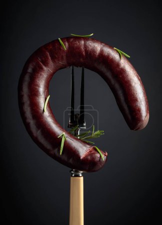 Téléchargez les photos : Pouding noir ou saucisse de sang avec romarin sur une fourchette. - en image libre de droit