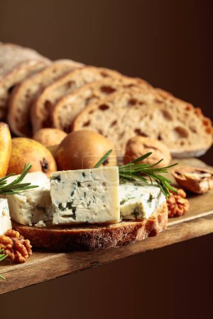 Foto de Sandwich con queso azul y peras. En un viejo pan de mesa de madera, queso azul, peras, nueces y romero. - Imagen libre de derechos