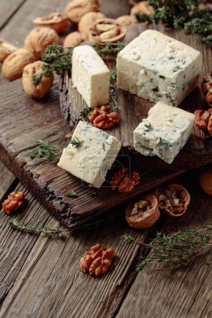 Photo for Blue cheese with walnuts and thyme on an old wooden table. - Royalty Free Image