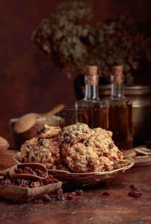 Photo for Oatmeal raisin cookies and kitchen utensils on a brown table. - Royalty Free Image
