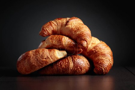Photo for Freshly baked croissants on a black ceramic table. Traditional French kitchen. - Royalty Free Image