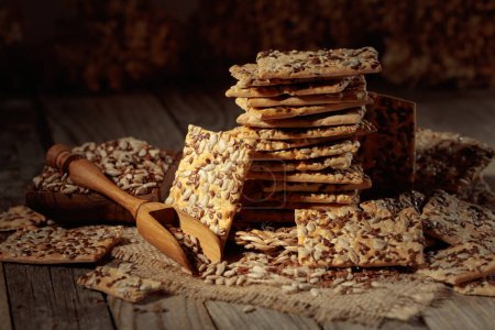 Téléchargez les photos : Crispy crackers with sunflower and flax seeds on an old wooden table. Simple healthy food. - en image libre de droit