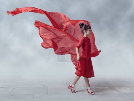 Téléchargez les photos : Fille dans une robe rouge avec tissu volant sur un fond de ciel brumeux. - en image libre de droit