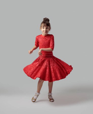 Téléchargez les photos : Fille dansante en robe rouge sur un fond gris. - en image libre de droit