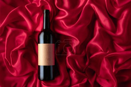 Foto de Bottle of red wine with an empty label on a satin background. Top view. - Imagen libre de derechos