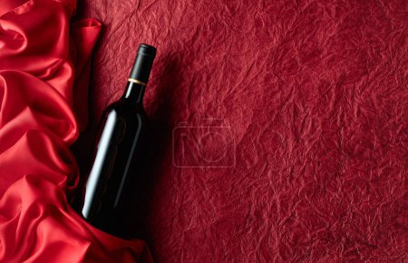 Téléchargez les photos : Bouteille de vin rouge sur un vieux fond rouge. Vue du dessus. - en image libre de droit