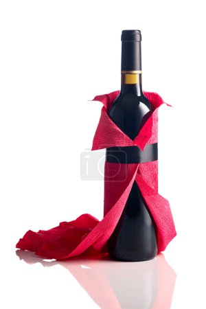 Téléchargez les photos : Bouteille de vin rouge enveloppée dans du papier crêpe isolé sur un fond blanc. La bouteille ressemble à une femme dans une robe de soirée rouge. - en image libre de droit