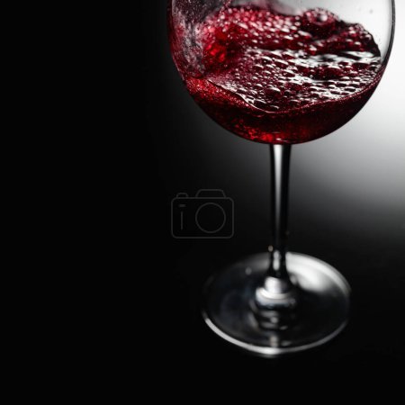 Téléchargez les photos : Gros plan de vin rouge coulant sur un fond noir. Espace de copie. - en image libre de droit
