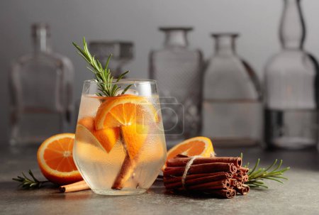 Téléchargez les photos : Cocktail gin tonic avec glace, romarin, cannelle et orange sur une table en pierre dans un bar. - en image libre de droit