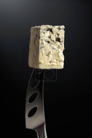Téléchargez les photos : Du fromage bleu sur un couteau. Fond noir. - en image libre de droit