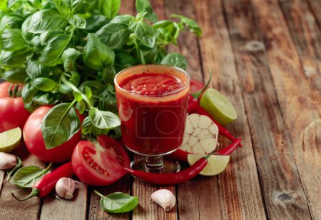 Téléchargez les photos : Sauce tomate et ingrédients. Tomates fraîches, poivrons rouges, ail, basilic et citron vert sur une vieille table en bois. - en image libre de droit