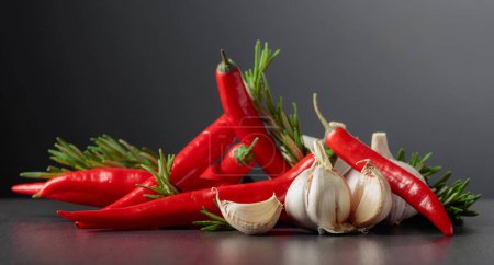 Photo for Red hot chili peppers, garlic, and rosemary on a black background.Copy space. - Royalty Free Image